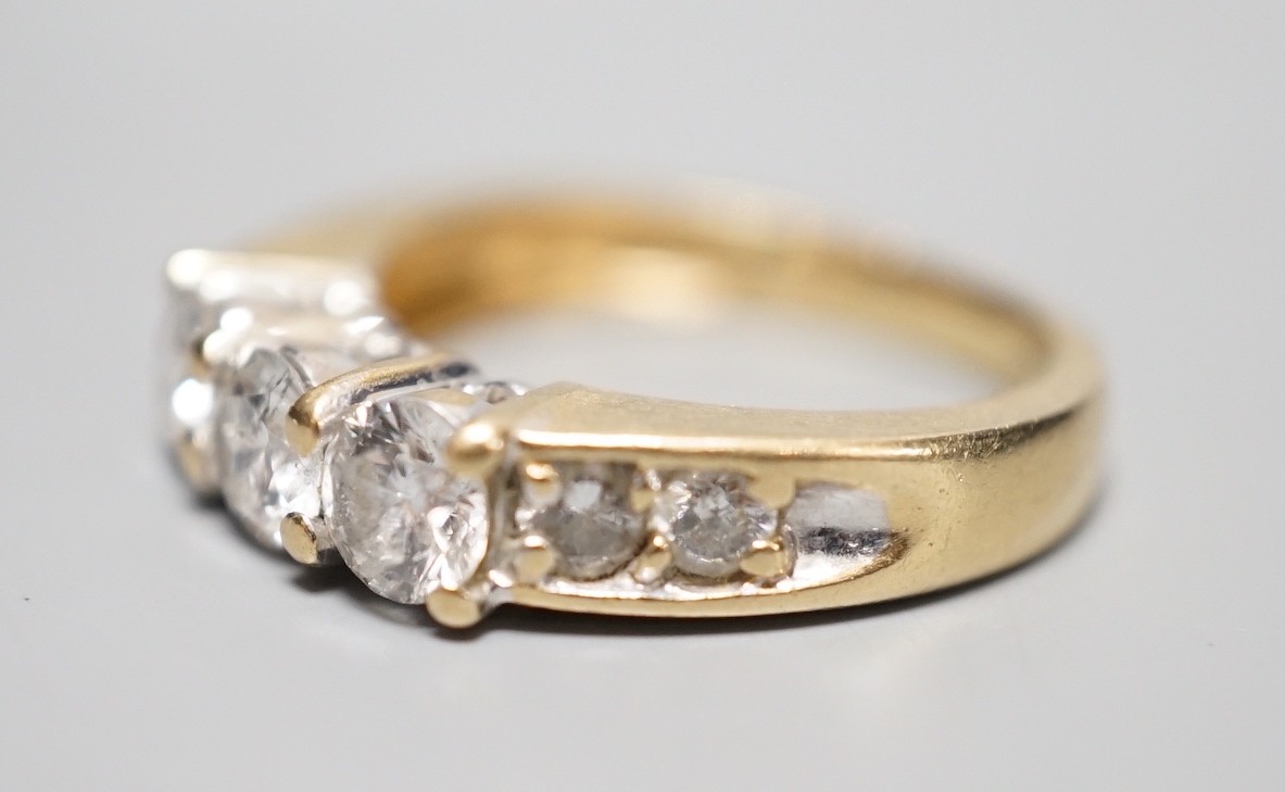A 14k yellow metal and three stone diamond ring, with four stone diamond set shoulders, size K, gross weight 4.3 grams